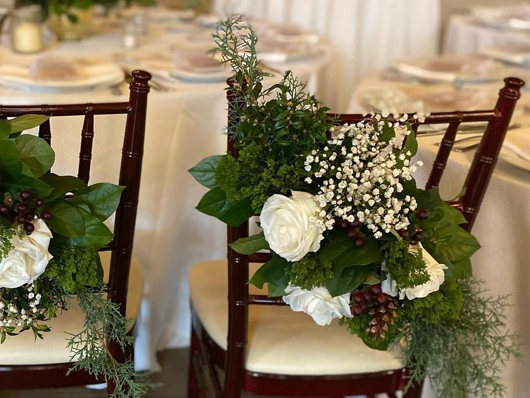 Decorated chairs with floral arrangements at wedding reception.